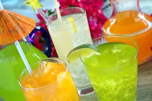 A selection of summer drinks with ice including lime, orange and lemon.