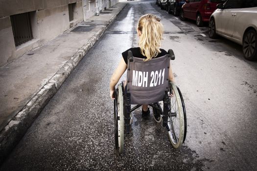 A girl sitting in a wheelchair with her back to the camera