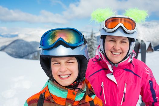 Portrait closeup of happy smiling girl in ski goggles and a helmet with his mother