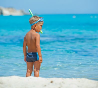 Back view of cute boy snorkelling ready swim in the transparent sea.
