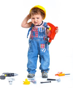 Little builder. Baby boy in a helmet plays in the builder with tools. Isolated over white.