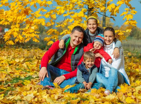Happy family with three kids at beautiful autumn park