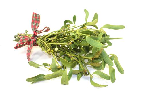 Mistletoe with berries and ribbon on a light background