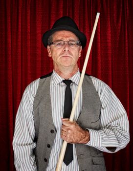Serious retro style man with pool cue on curtain background