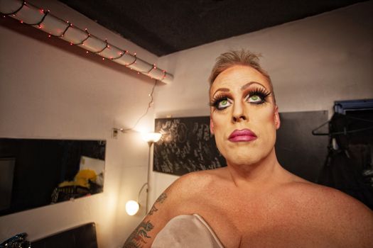Serious male in drag waiting in dressing room