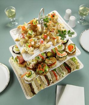 Delicious assorted finger food and sandwiches on a three tier stand.