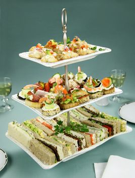 Delicious assorted finger food and sandwiches on a three tier stand.