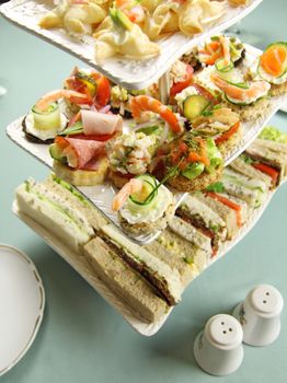 Delicious assorted finger food and sandwiches on a three tier stand.