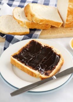 The iconic Australian spread vegemite on to a slice of fresh bread.