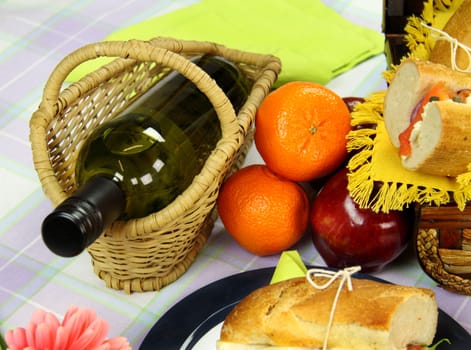 Bottle of white wine in a cane cradle with picnic food.