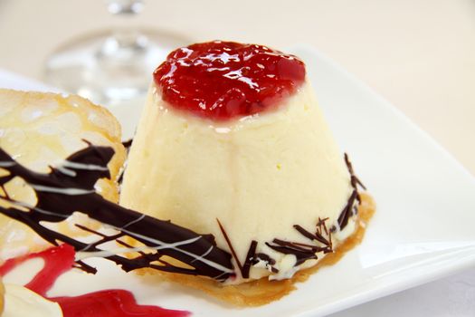 White chocolate mousse with biscuit topped with strawberry sauce.