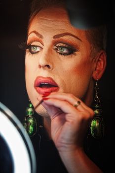 Man in drag with lipstick and mirror