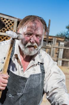 Old West Blacksmith Holds Hammer While Smoking a Cigar