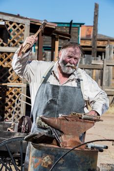Old West Blacksmith Swings Hammer at an Anvil