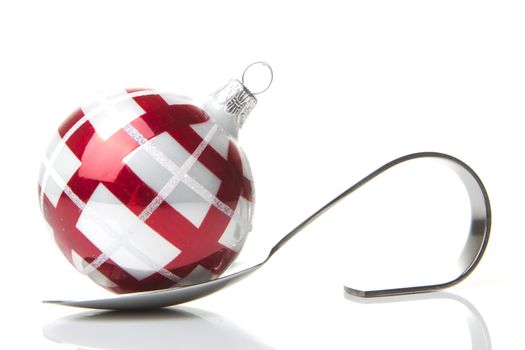 red and white christmas bauble on a spoon isolated with white background