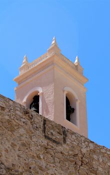 Torreon de la Pena ancient fortified wall and the tower bell of parish church Nuestra Senora de las Nieves, located in the Calp old town. Spain
