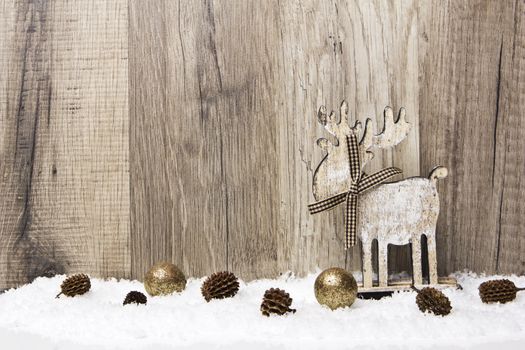 christmas decoration with wood background, snow, elk, christmas baubles gold and pine cones