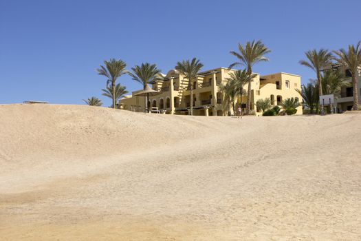 Building at the end of a desert with palm trees