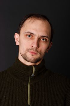 young man in an old sweater on a dark background. studio portrait