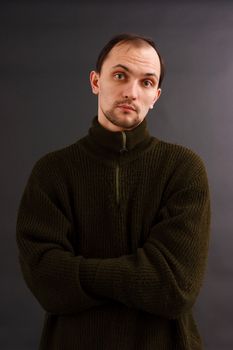 young man in an old sweater on a dark background. studio portrait