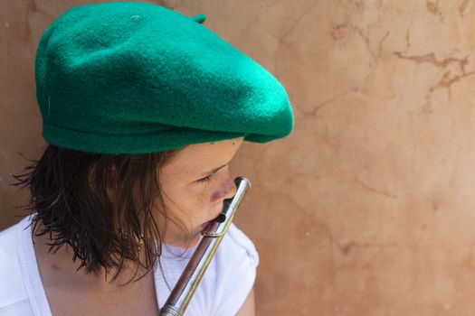 Young girl with green beret hat plays practice the flute music wind instrument .