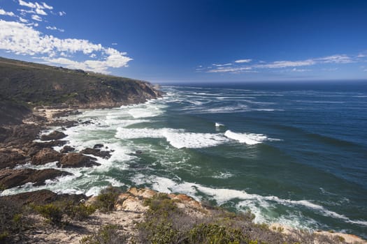 High rock coastline cliffs overlooking blue ocean waves.