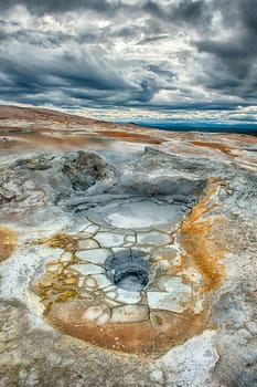 Mudpot in the geothermal area Hverir, Iceland. The area around the boiling mud is multicolored and cracked. HDR image