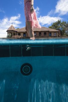 Unidentified girl tests water temperature of pool to swim.