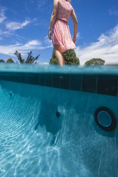 Unidentified girl tests water temperature of pool to swim.