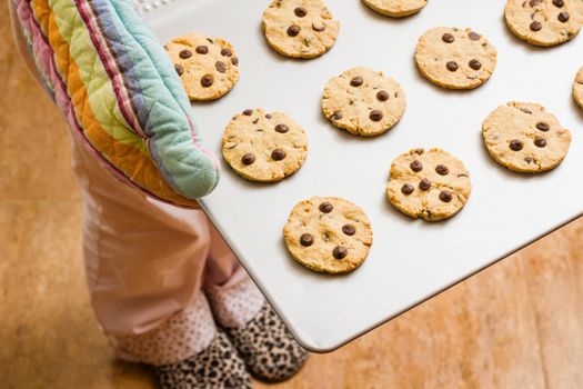 Woman holding a tray with homemade baked cookies with colorful kitchen gloves