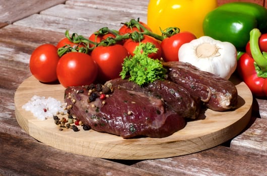 meat with fresh vegetables on wooden board