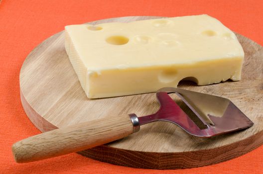 Cheese with a knife on a wooden board