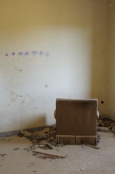 Armchair facing the wall. Empty room in abandoned house interior.