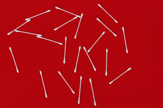 Ear buds white cotton swabs on red background.