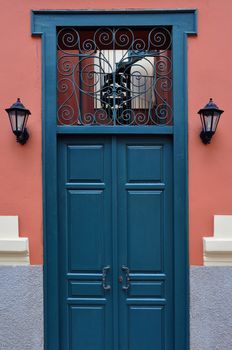 Blue wooden door with antique wrought iron pattern. Architectural detail.