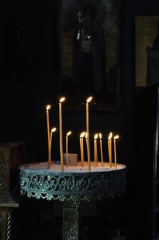 Vintage byzantine manouali candle stand in dark orthodox church interior.