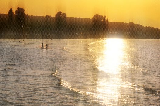 Children playing at the beach. Sunset light leaking on sea water vintage style photo composite.