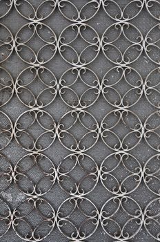 Vintage iron door frame with circles pattern detail and stained glass background.