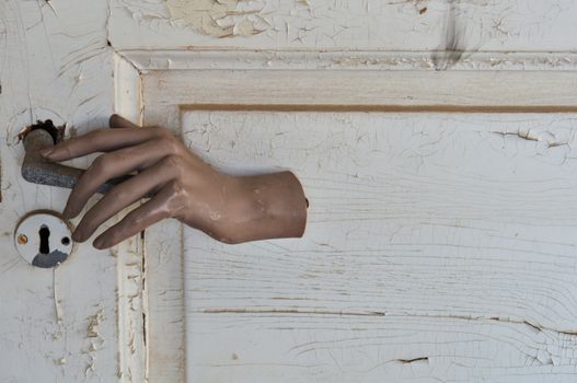 Doll hand opening a closed door in haunted house.