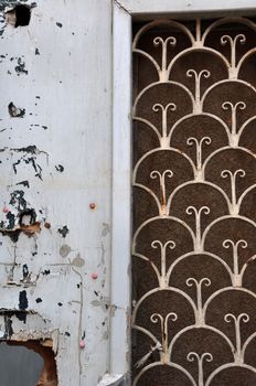 Broken wooden door with vintage rusty metal pattern and peeling paint. Abstract background.
