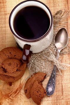 Arrangement of Rustic Cup of Black Tea with Chocolate Chip Cookies and Tea Spoon closeup on Wooden background. Top View