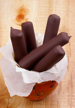 Ice Cream Sticks Glazed in Dark Chocolate in Bowl on Wooden background