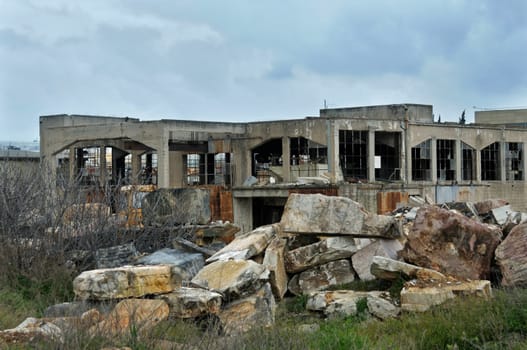 Abandoned marble processing factory exterior and cloudy sky. Industrial decay.