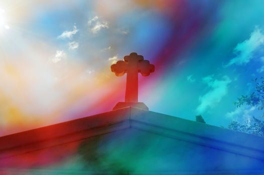 Mausoleum cross against blue sky. Bright sunlight lens flare through painted glass digital composite abstract blur.