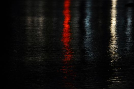 Colorful city lights reflected on dark sea water. Night abstract background.