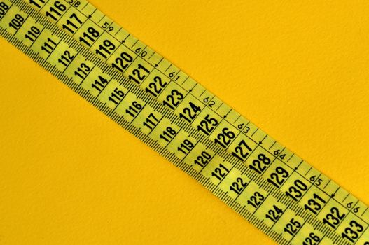 Plastic tape measure inches and centimeters. Abstract numbers yellow background.