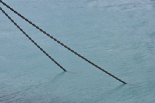 Rusty ship chain anchor submerged in sea water abstract background.