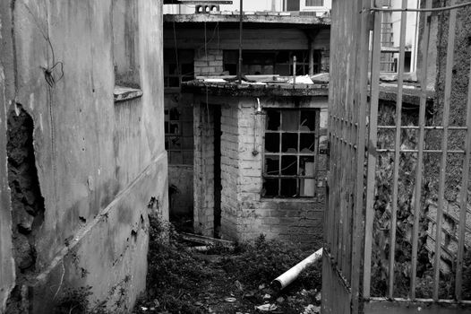 Rusty gate to an abandoned warehouse. Black and white.