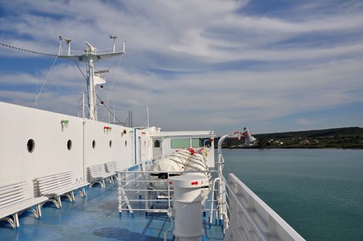 Ship deck with benches, portholes and inflatable liferafts. Sea and sky horizon travel background.