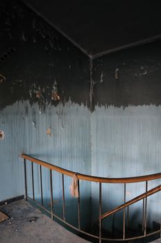 Paint stained wall and vintage staircase in abandoned house interior.